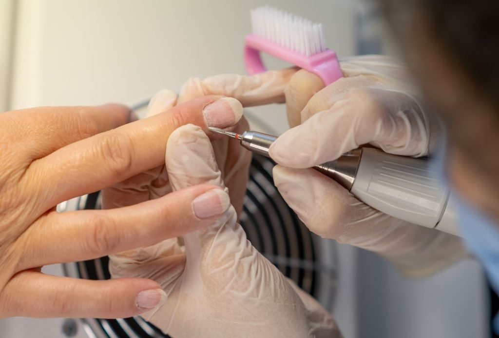 Nail technician carefully shaping a client's nails during a manicure